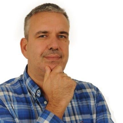 Portrait of Pierre-Marie Coupry in a blue plaid shirt, hand under his chin
