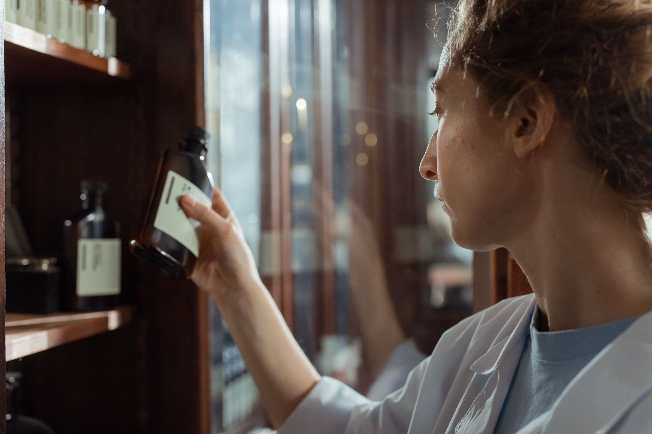 A pharmacist in a lab coat takes a medicine box from a shelf