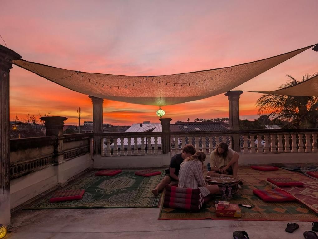 The rooftop terrace of Monkey Guesthouse at sunset, with cushions and rugs under a shade sail