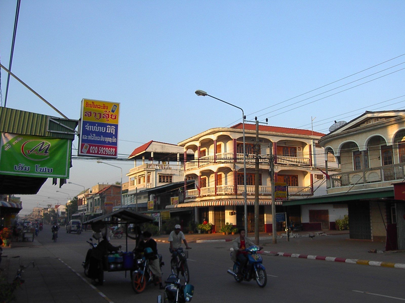 A downtown street with balconied buildings and motorbikes on the road