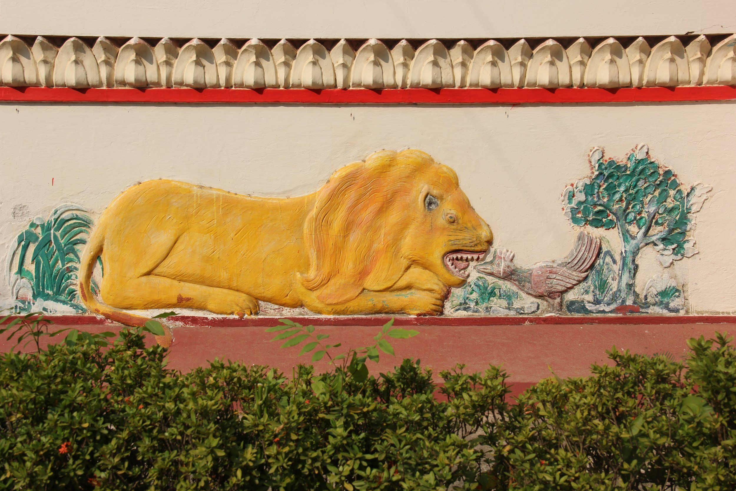 A gilded lion in relief on the outer wall of Wat Sainyaphum