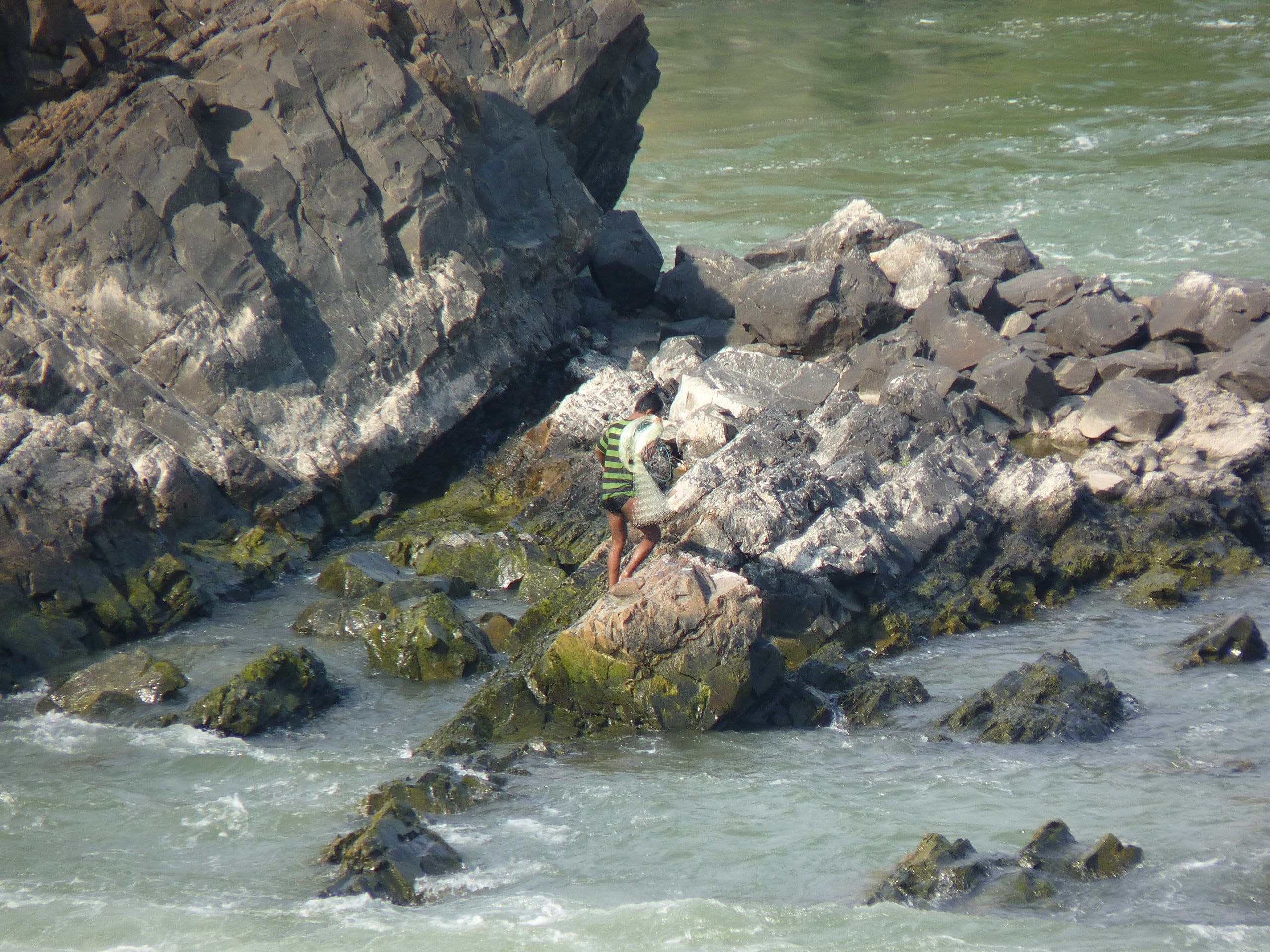 A fisherman on the rocks beside Phapheng falls