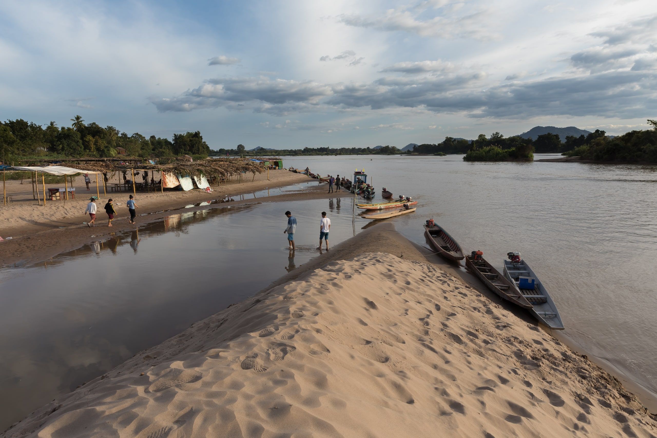 Long boats pulled up on a sandy beach at sunset in the 4,000 Islands