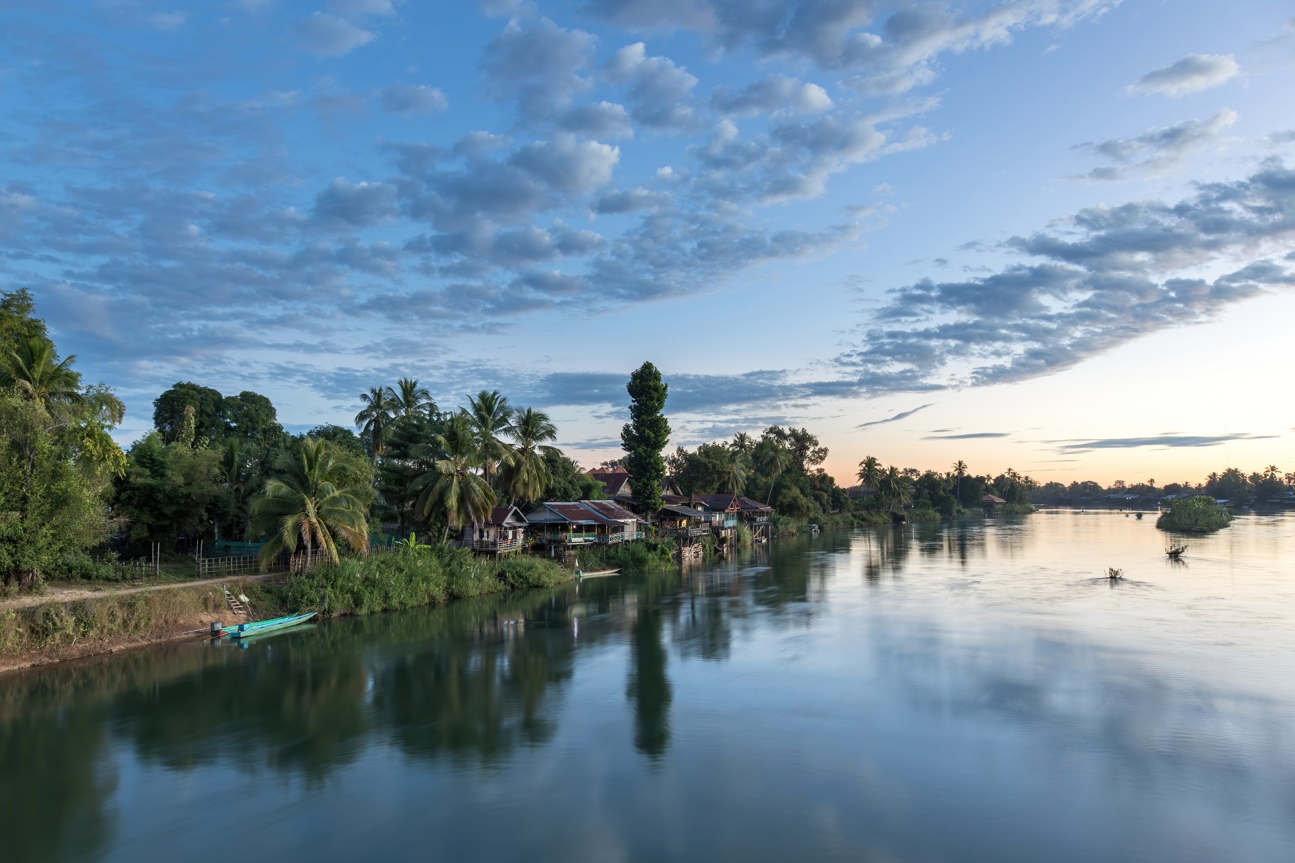 Houses and long boats on the Don Det bank at sunrise