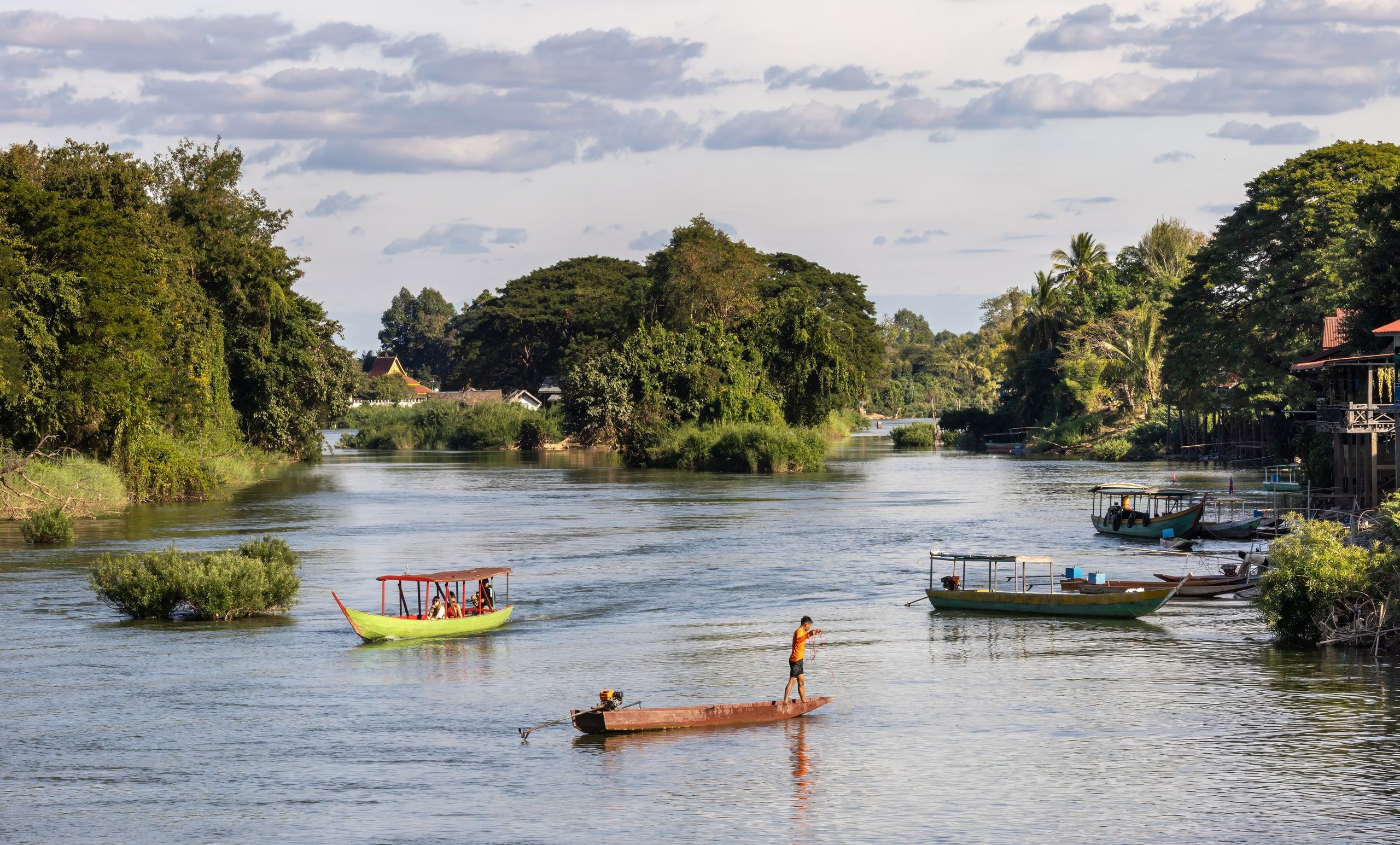 A fisherman standing in his boat on a Mekong channel at Don Det