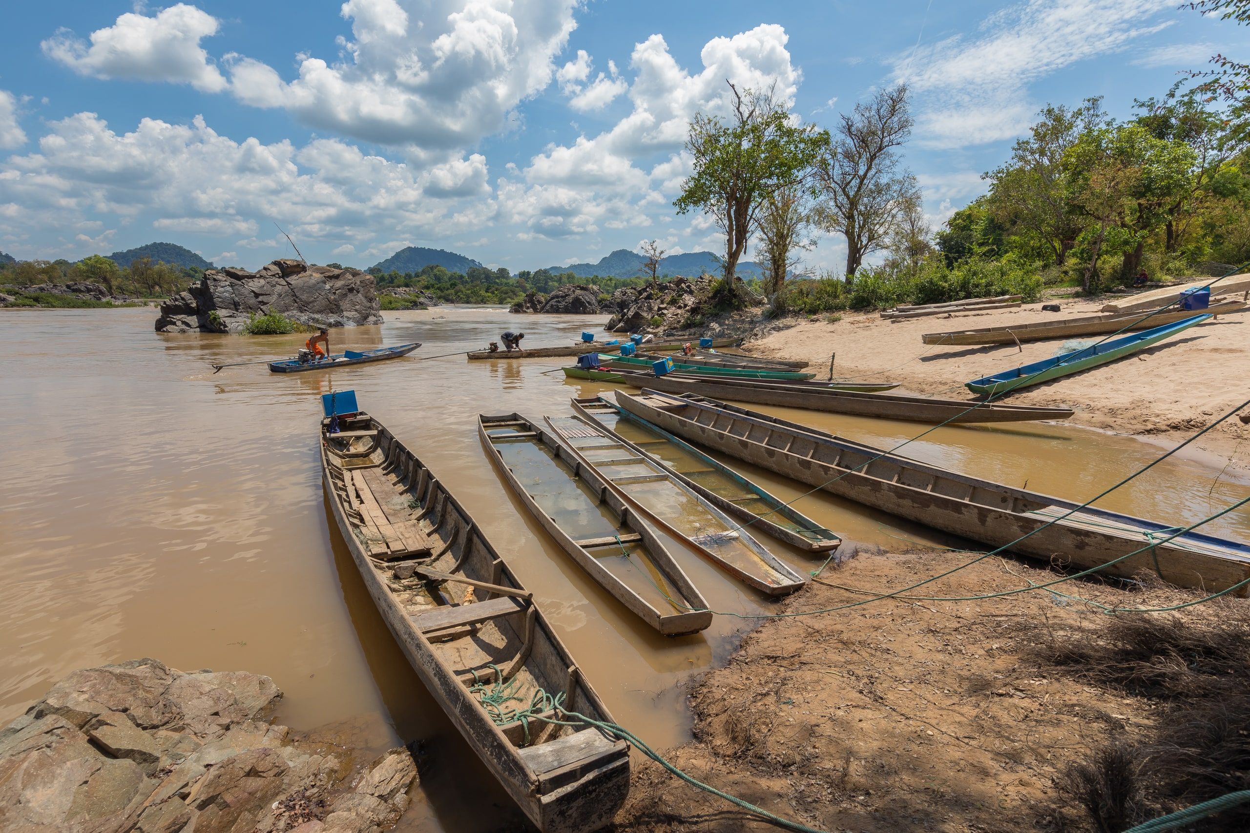 Long boats moored on a Don Khon bank, two fishermen on the water