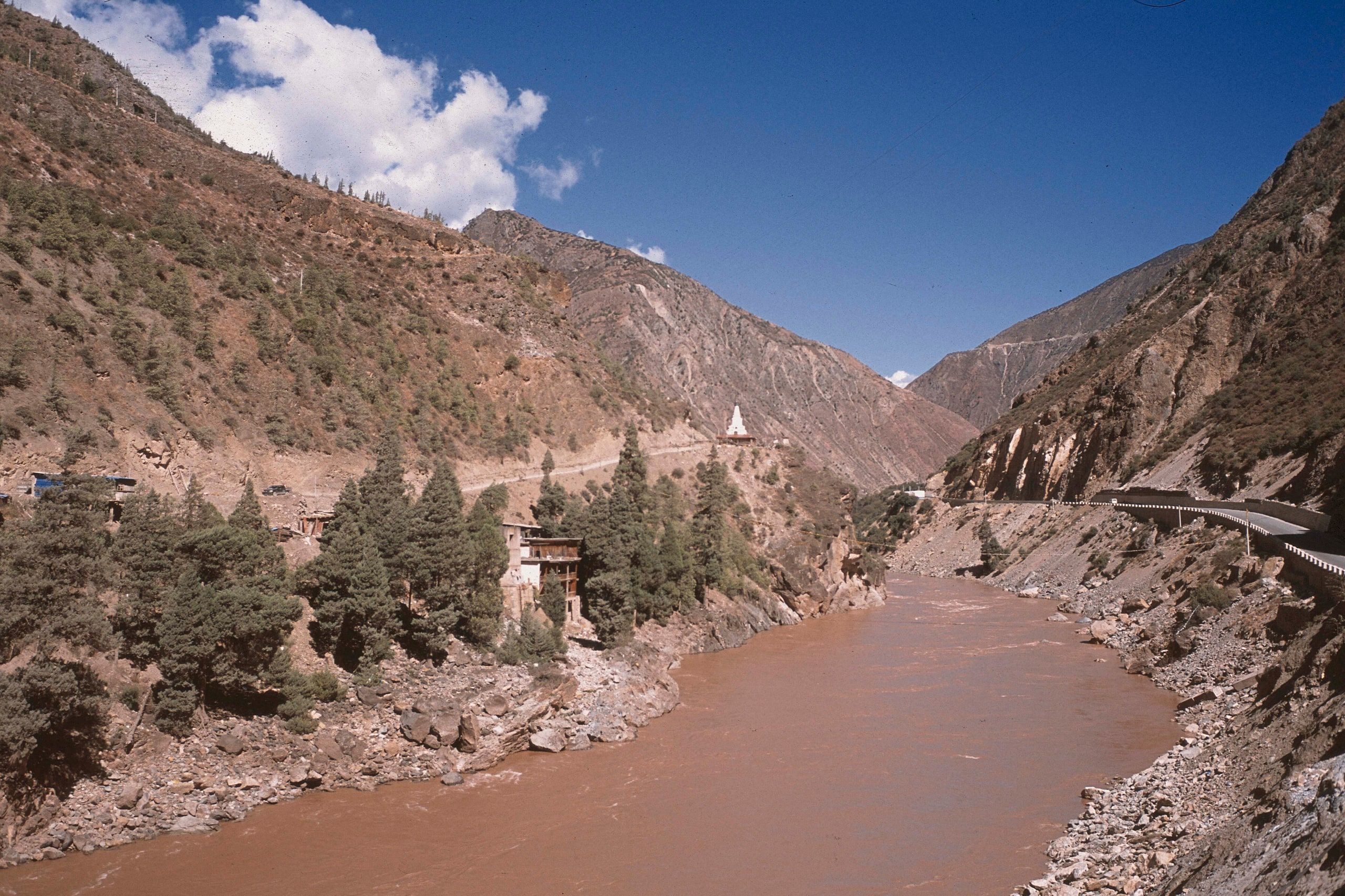 The Mekong, called the Lancang in China, flows at the bottom of a gorge in northern Yunnan between dry slopes; a white chorten stands above the bank