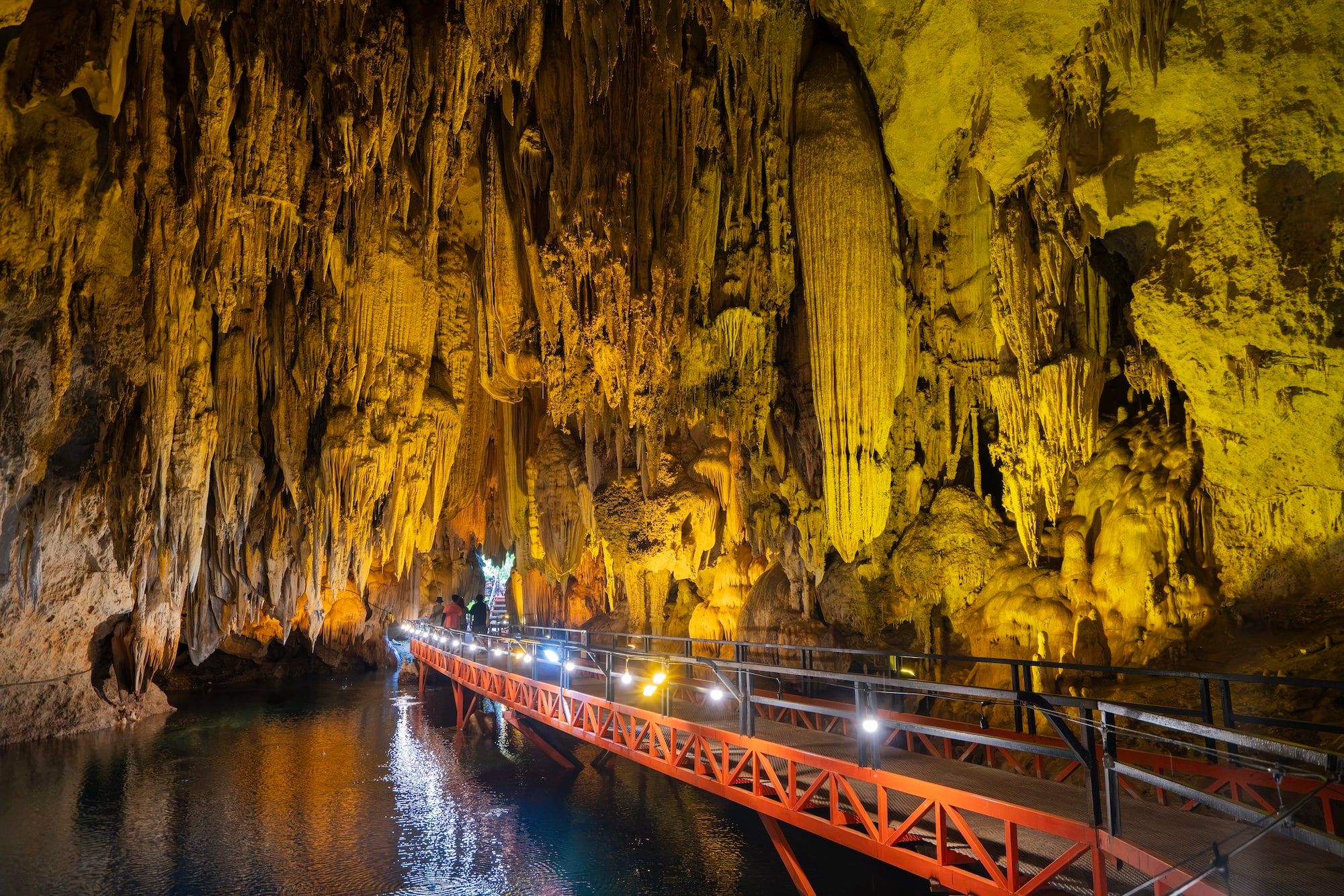 Des stalactites éclairées et une passerelle au-dessus de l'eau, dans une grotte du Khammouane
