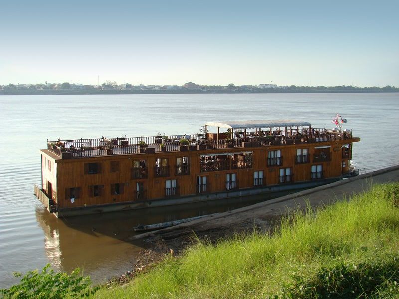Un bateau-hôtel en bois amarré sur le Mékong à Thakhek, la rive thaïe en face