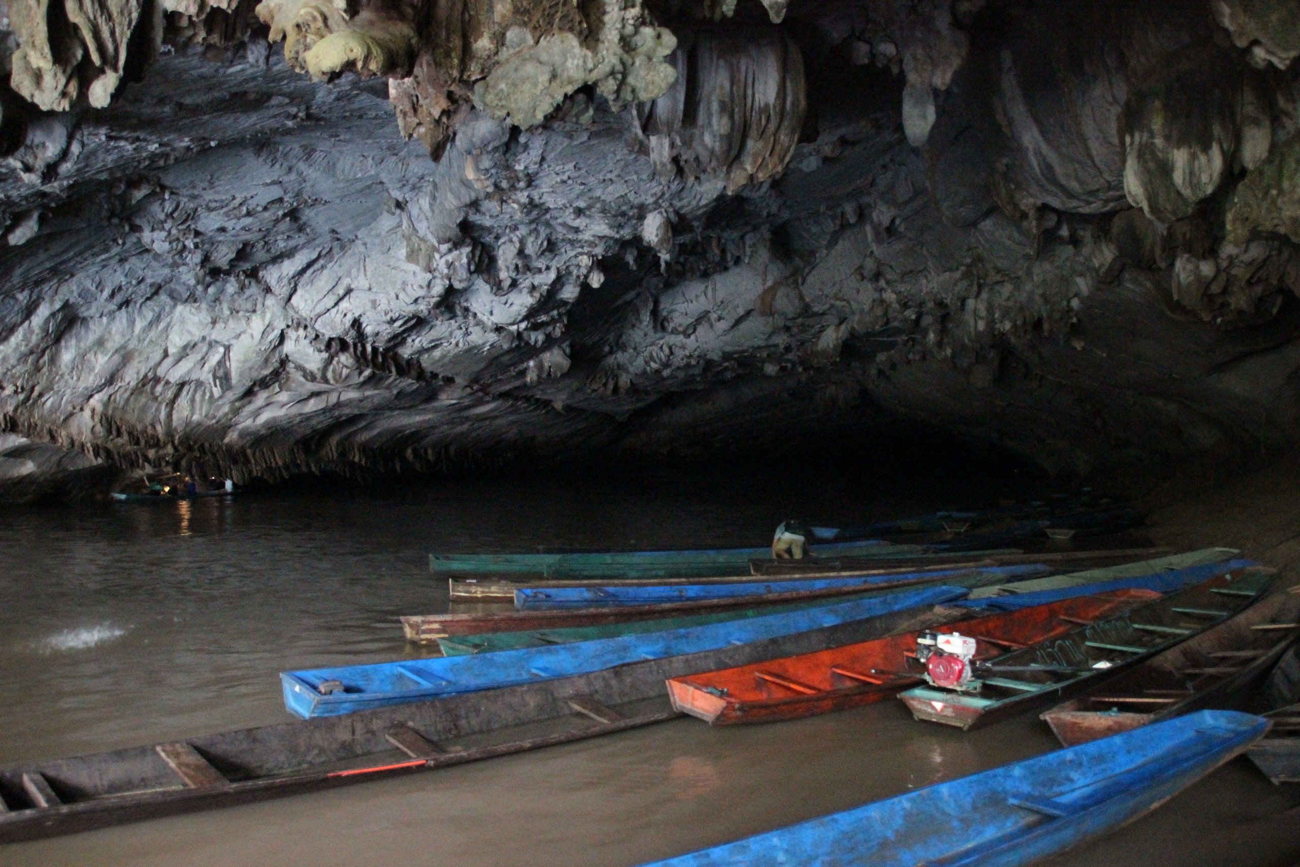 Des pirogues amarrées sous la voûte de la grotte de Kong Lor