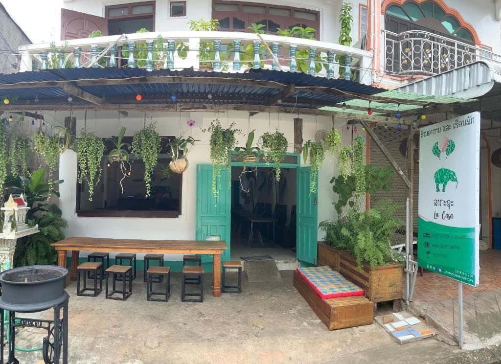 L'entrée de l'auberge La Casa, ses plantes suspendues et ses tables hautes