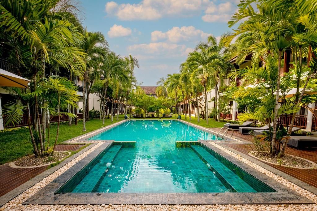 La piscine du Green Park entre deux ailes à balcons de bois, bordée de palmiers