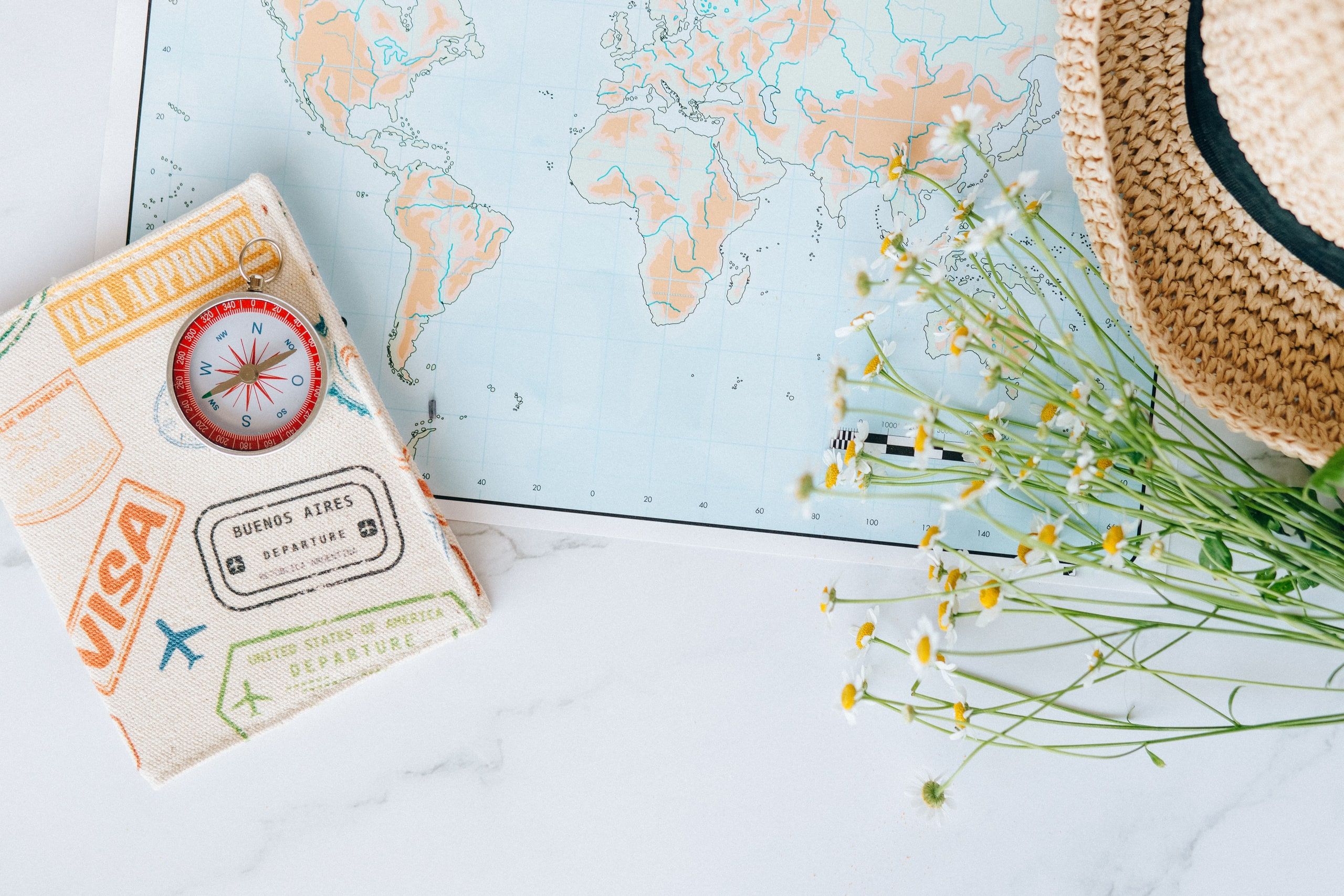 A passport, a compass and a world map on a table